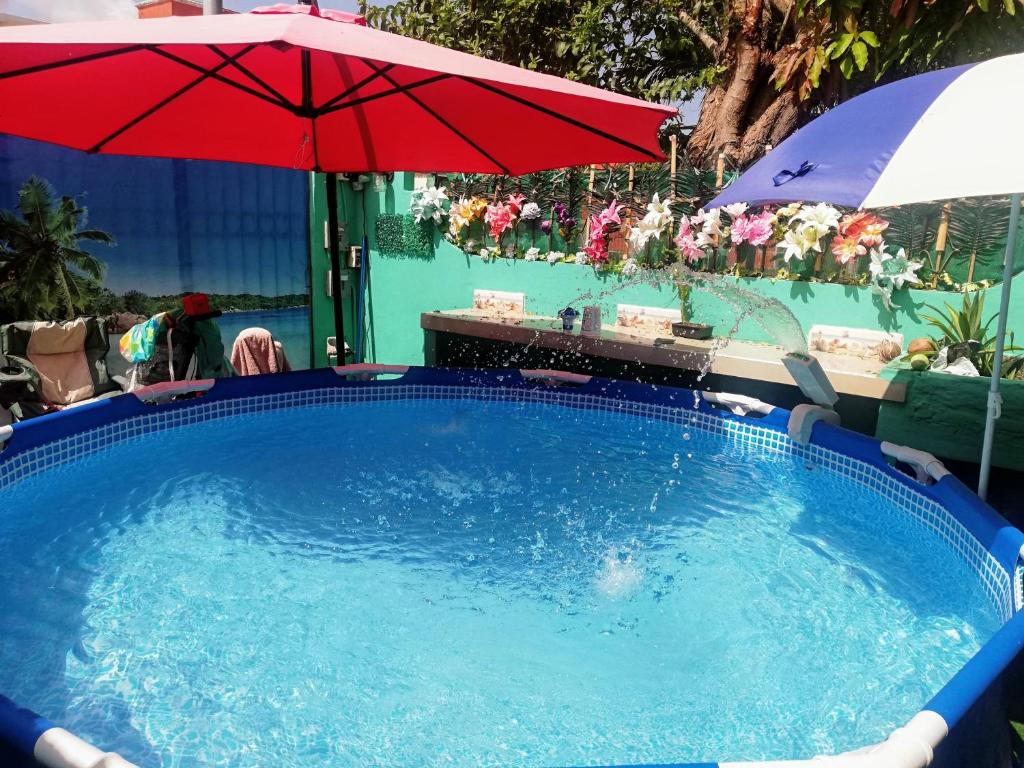 una piscina con una sombrilla roja y una mesa en Style House in Cancun en Cancún