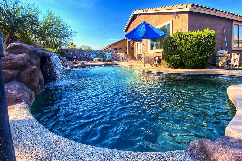 una piscina con cascada en un patio trasero en Contemporary Goodyear Refuge with Sunny Private Pool, en Liberty