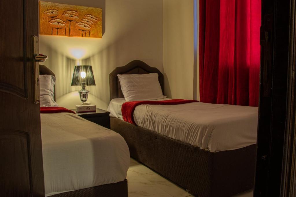 een slaapkamer met 2 bedden en een rood gordijn bij Magic Suite Plus For Hotel Apartment in Koeweit