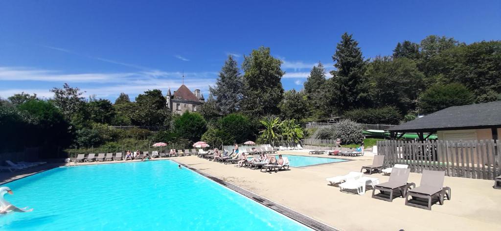 una piscina con sillas y gente sentada a su alrededor en Chalet-dordogne B10 camping Château Le Verdoyer - Champs Romain, Dordogne, en Puyhardy