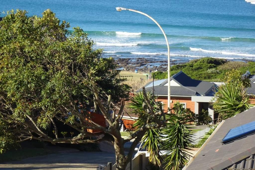 a street light and a tree in front of the ocean at Lovely 2-bedroom apartment with free parking on premises in Jeffreys Bay