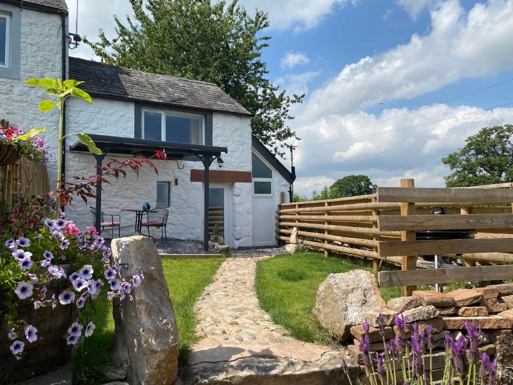 a cottage with a fence and flowers in front of it at Delightful One Bed Lake District Cottage in Penrith