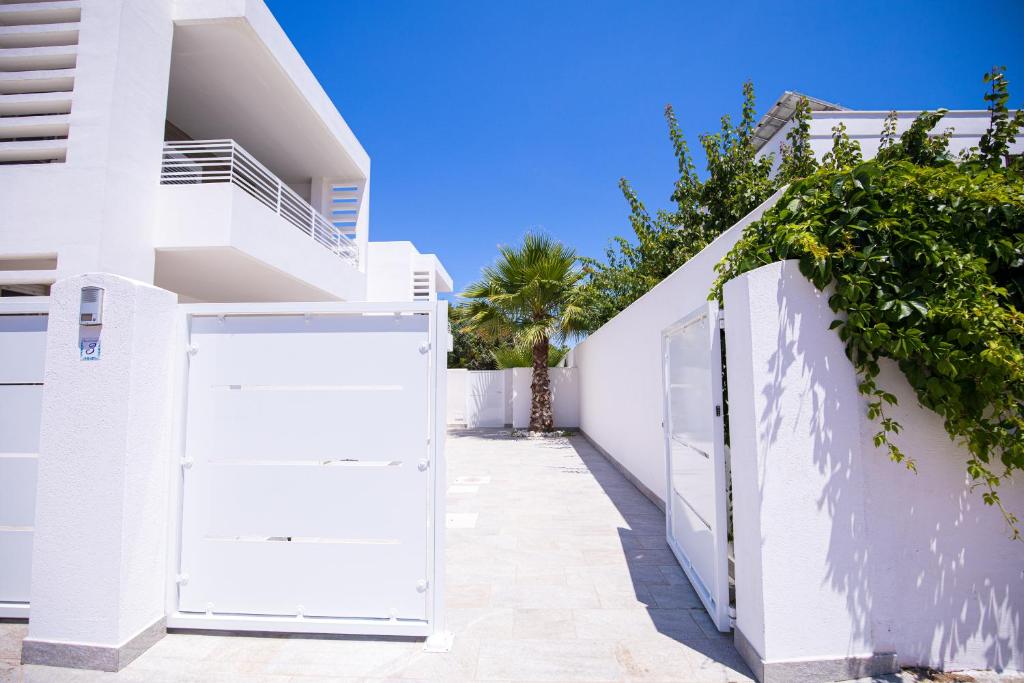 a white house with a gate and a fence at Donnosanto Residence Pantanagianni in Torre Santa Sabina