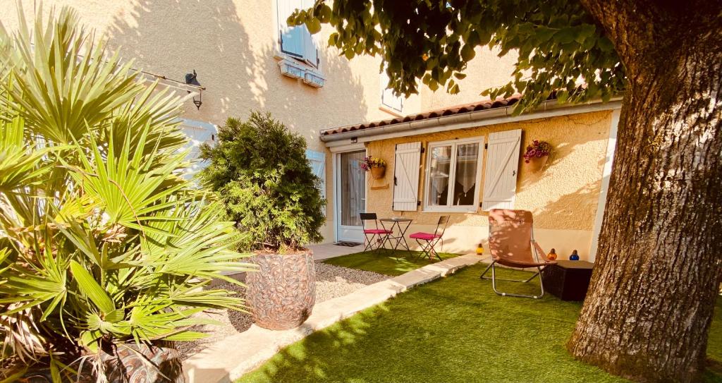 un jardin avec des chaises et des plantes devant une maison dans l'établissement Maison d'hôtes chez Aud, à Dagneux