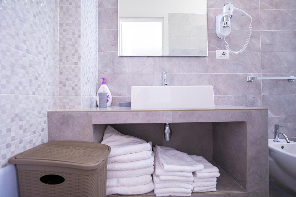 a bathroom with a sink and a pile of towels at Donnosanto Residence Pantanagianni in Torre Santa Sabina