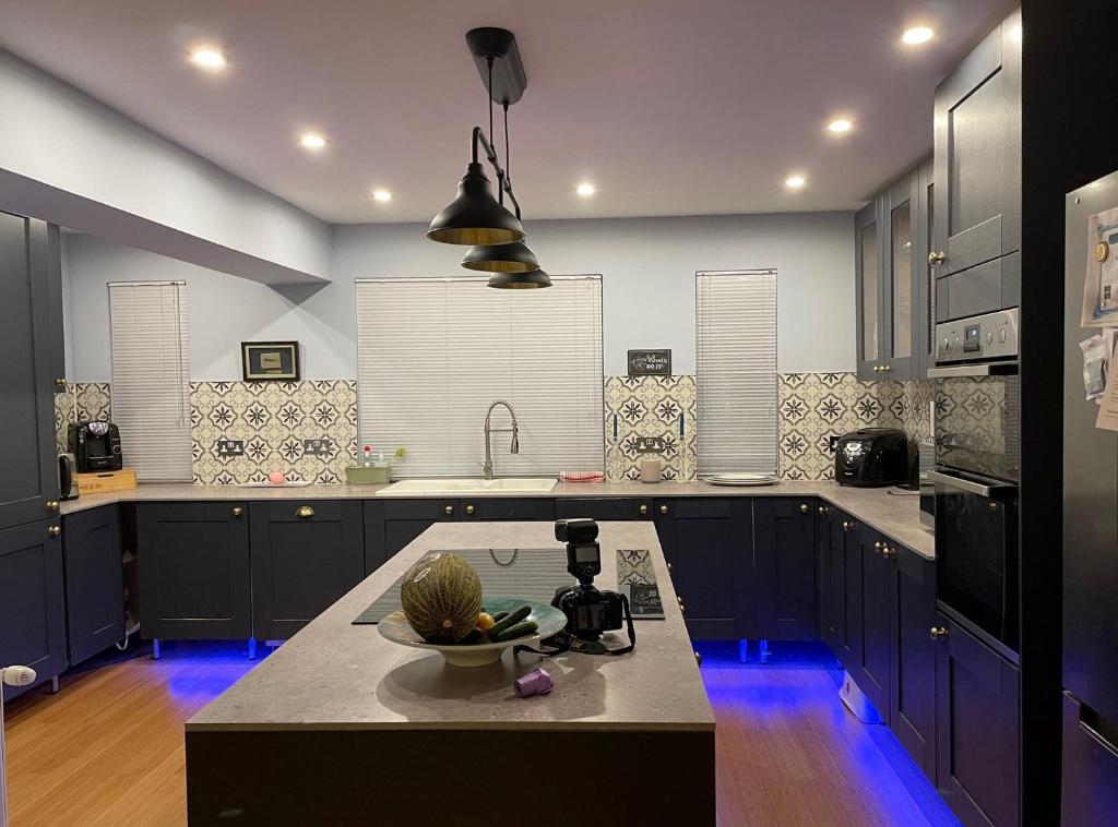 a kitchen with blue cabinets and a bowl of fruit on a counter at Home from Home - IONA - Private Members Club in Edinburgh