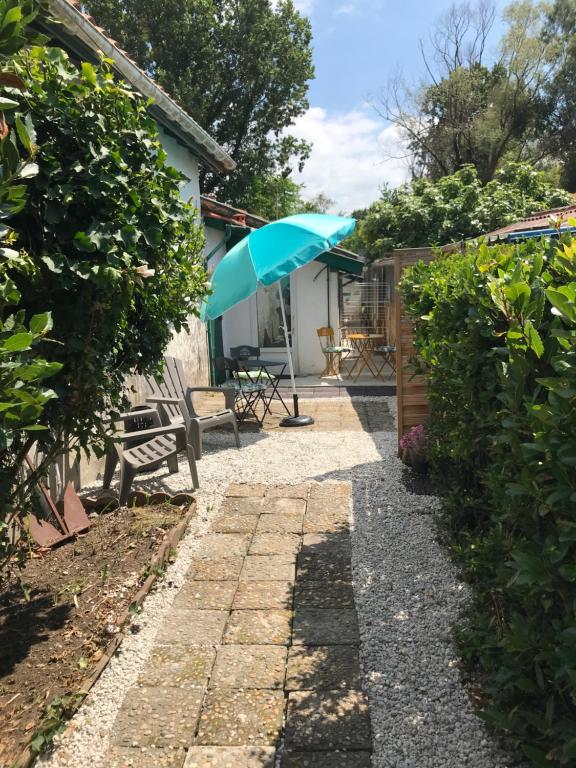 a patio with a blue umbrella and a bench at Appartement entre Océan et montagne 15bis avenue de Montbrun Anglet in Anglet