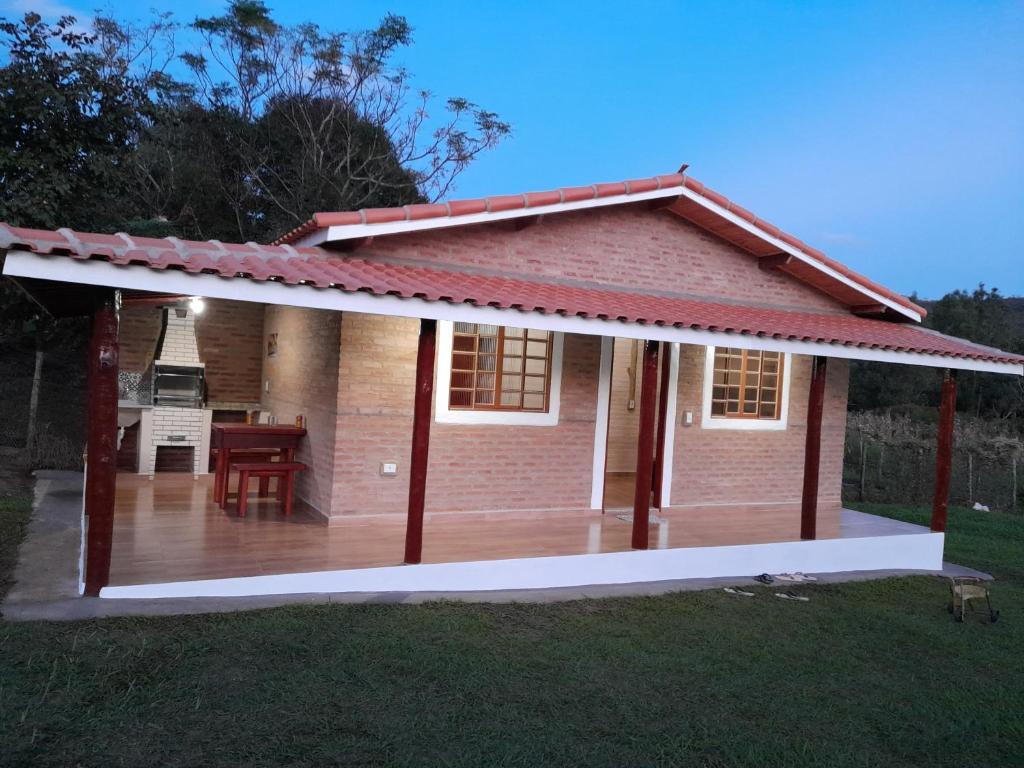 a small house with a deck in the yard at Chalé Recanto das palmeiras in São Thomé das Letras