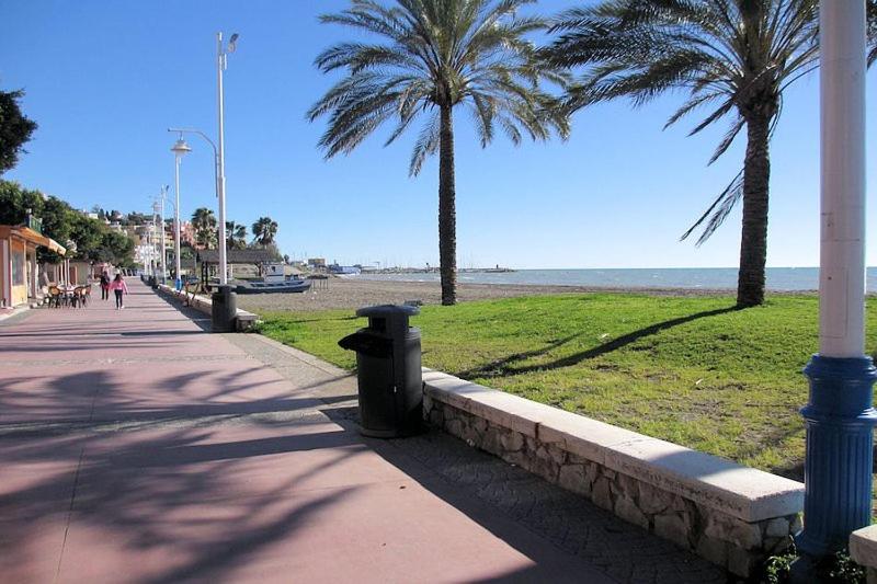 un marciapiede accanto a una spiaggia con palme di El Palo Estudio a Málaga