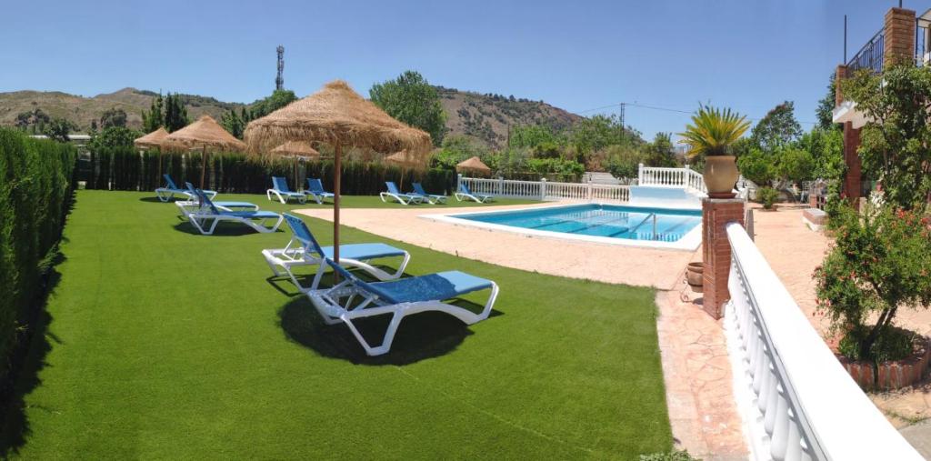 a row of lawn chairs next to a swimming pool at La Casita de Rufo in Granada