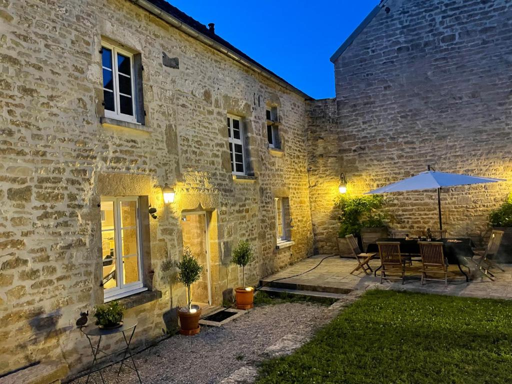 a brick building with an umbrella and a patio at La Closerie de Gigny Maison Templiere avec Piscine,jacuzzi in Gigny