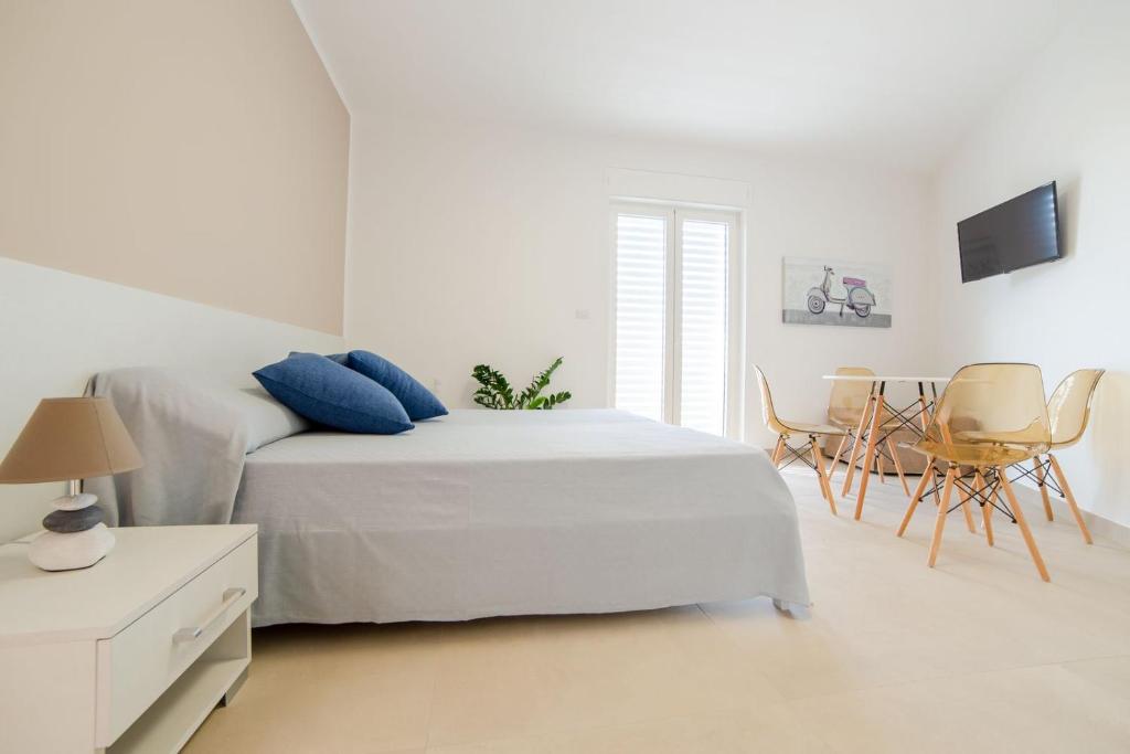 1 dormitorio blanco con 1 cama, mesa y sillas en Case Vacanza Apollo en Torre San Giovanni Ugento