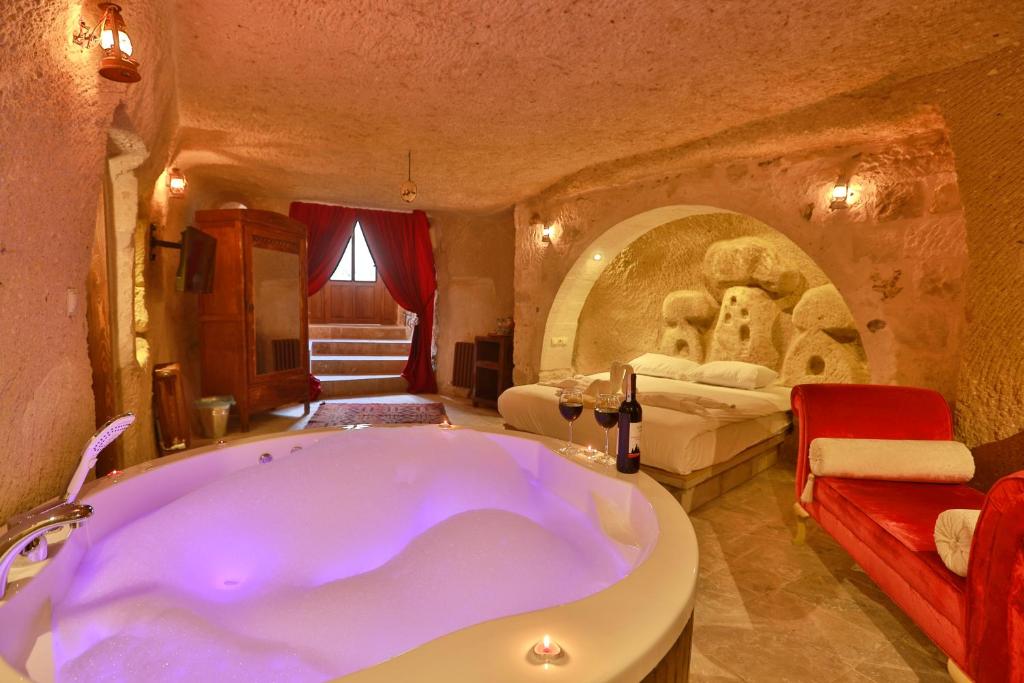 a large bathroom with a tub and a bedroom at Cappadocia Eagle Cave Inn in Nevşehir