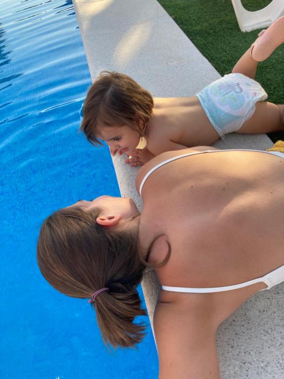 dos chicas jóvenes tumbadas junto a una piscina en Complejo turístico Fuente de la Salud, en Baena