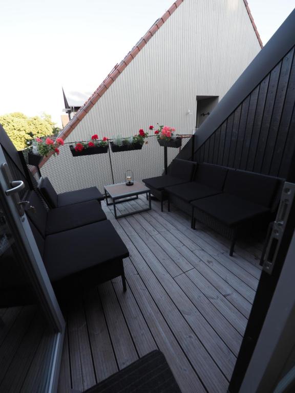 a balcony with two couches and a table and flowers at Apartamentai Juodkrantėje Saulės smūgis 2B 65 in Juodkrantė