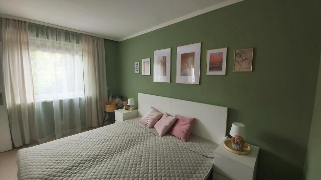 a bedroom with green walls and a bed with pink pillows at New Life Apartment in Latschach ober dem Faakersee