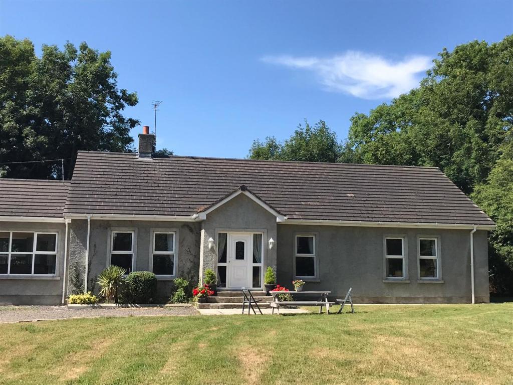 une maison grise avec une pelouse devant elle dans l'établissement Orchard Lodge, à Glenavy