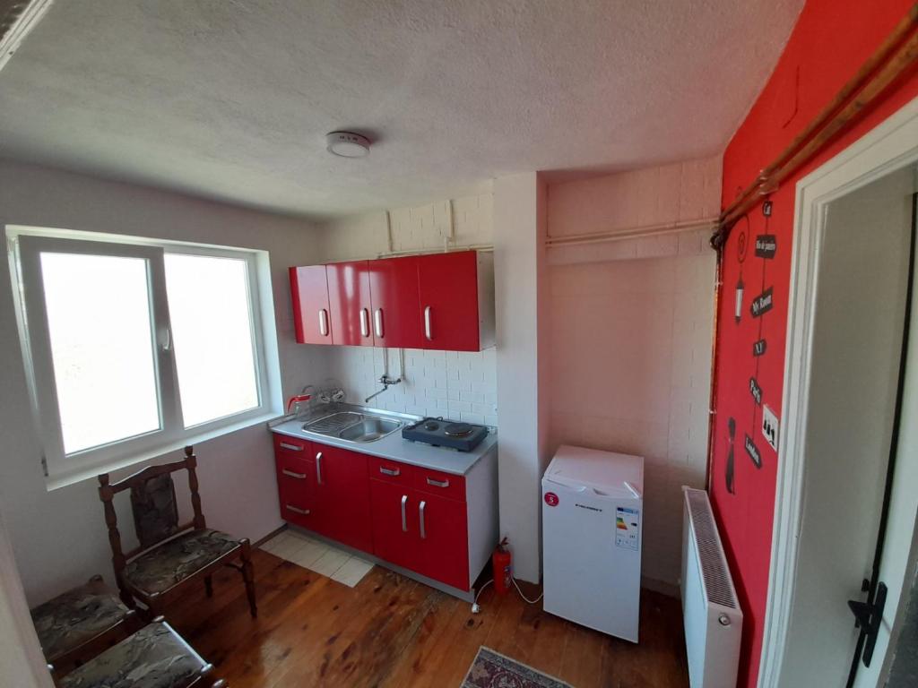 cocina con armarios rojos y nevera blanca en Apartments "La Štabe" - Kruševo, en Kruševo