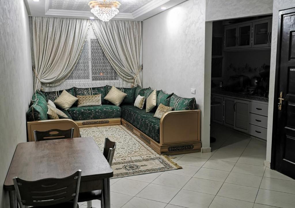 een woonkamer met een groene bank en een tafel bij Superbe appartement F3 tout confort in Agadir