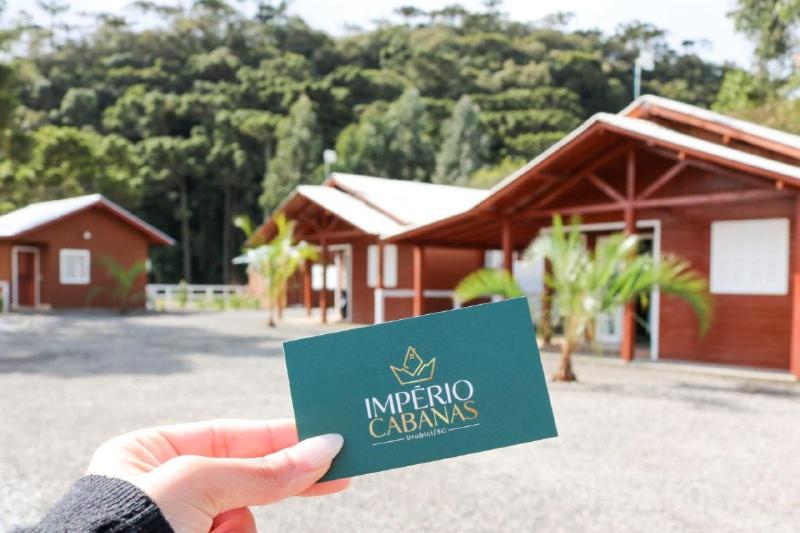 a person holding a green card in front of a building at Império Cabanas in Urubici