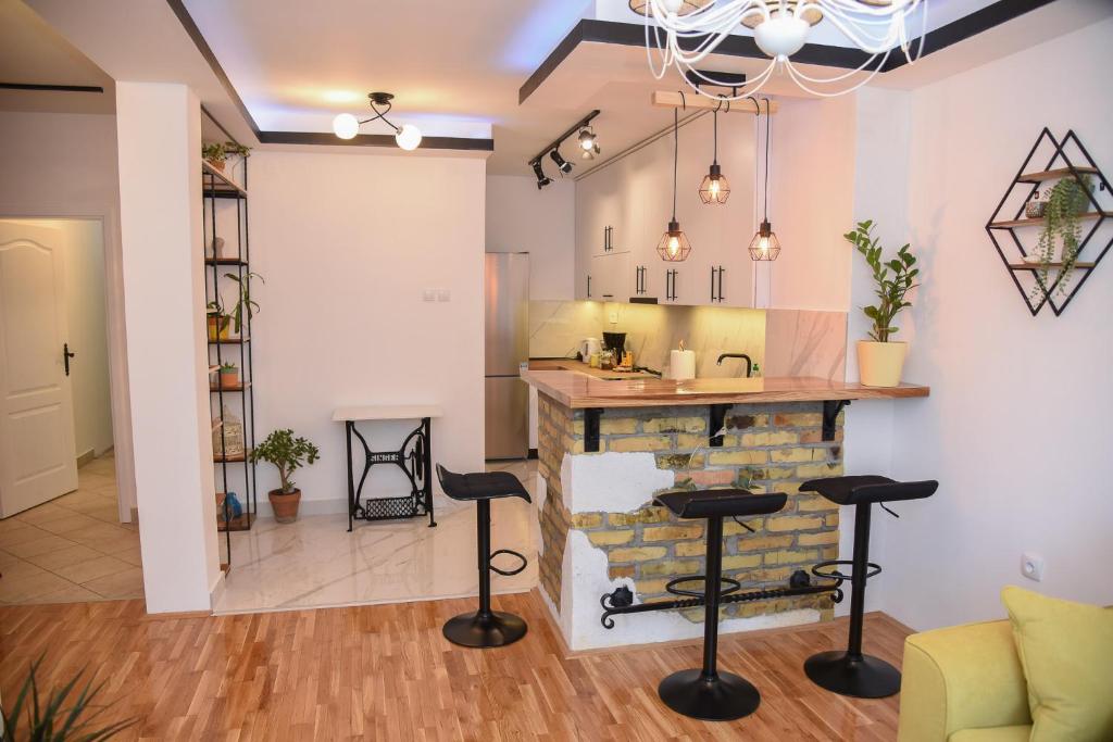 a kitchen and living room with a counter and stools at Garden Apartment - Oaza u centru grada in Novi Sad