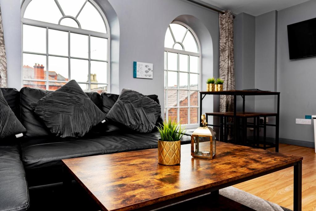 a living room with a black couch and a wooden table at The Glyndwr - Berwyn House in Wrexham