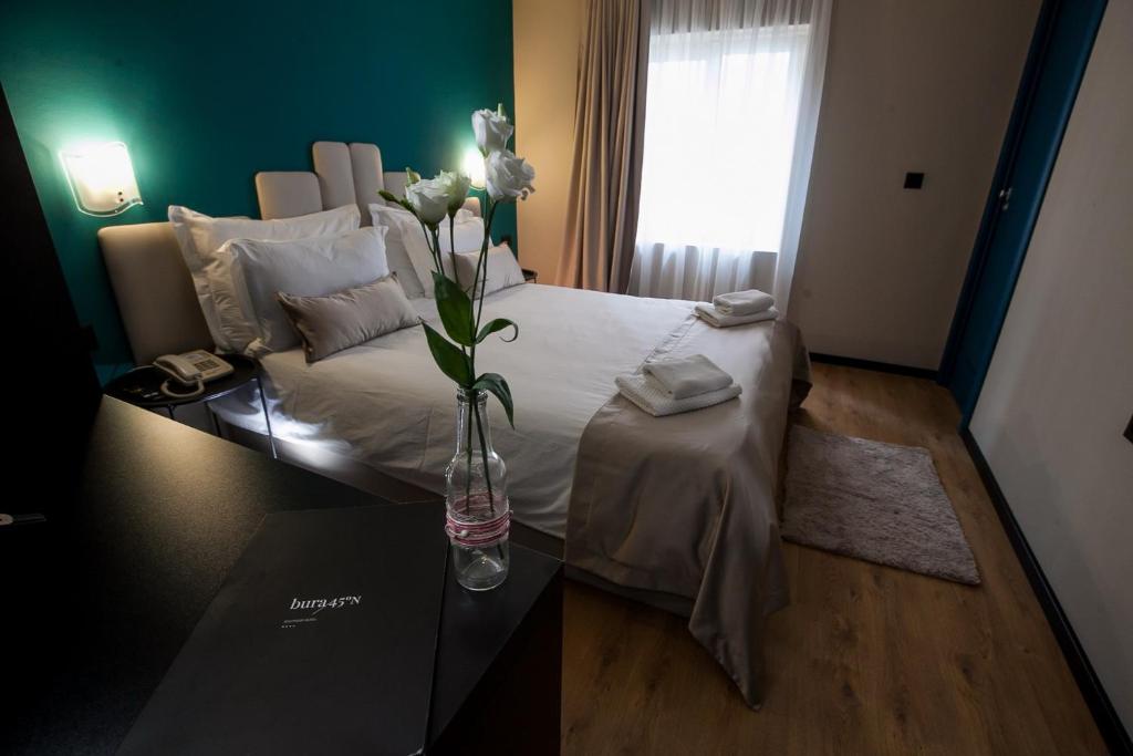 a bedroom with a bed with a vase of flowers on a table at Boutique Hotel Bura 45N in Senj