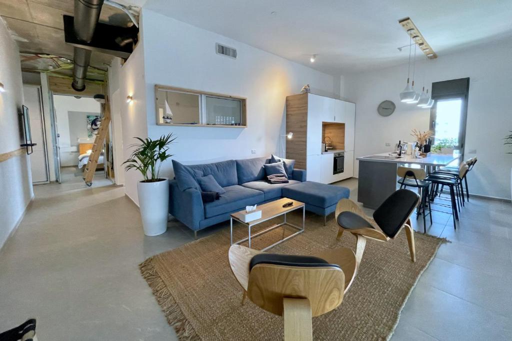 a living room with a blue couch and a table at Yamba יםבה באכזיב- פנטהאוז חדש ומפנק in Nahariyya