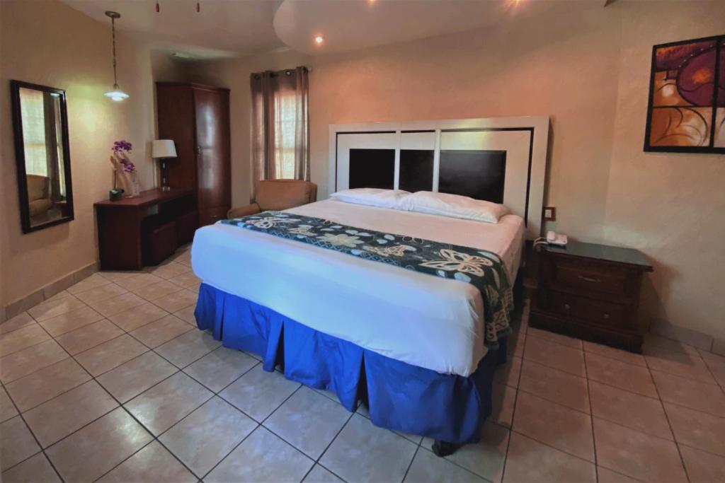 a large bedroom with a large bed and a chair at Hotel Hacienda del Viejo in Matamoros