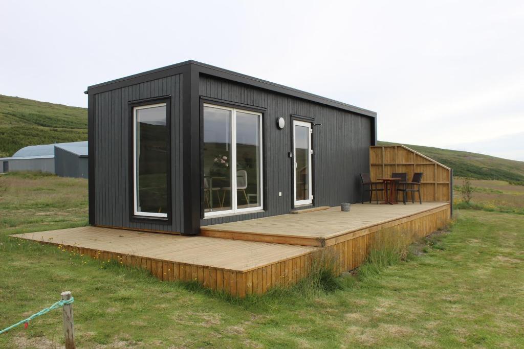 a black tiny house with a wooden deck at Studlagil Canyon Country Home in Grund