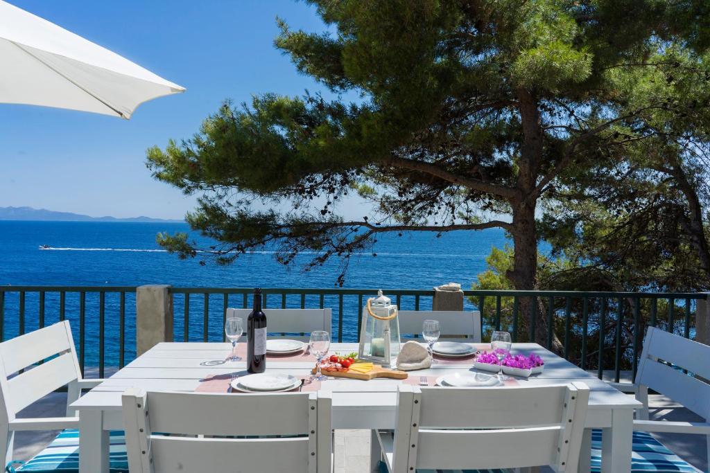 - une table et des chaises blanches avec vue sur l'océan dans l'établissement Apartments Bisko, à Prižba