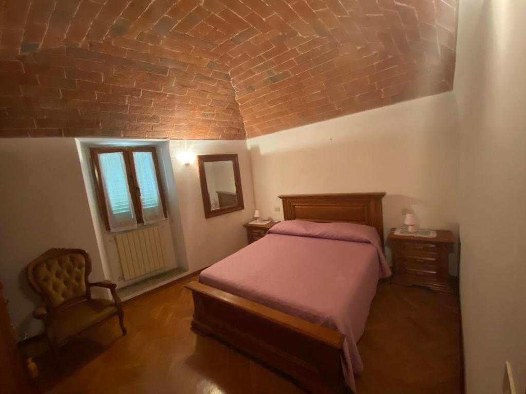 een slaapkamer met een bed en een bakstenen muur bij Lo Sdrucciolo in Laterina