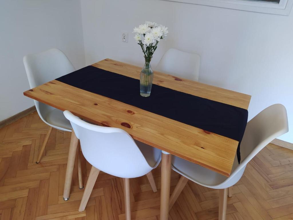 una mesa de madera con sillas blancas y un jarrón de flores en Apartament Aksamitny, en Toruń