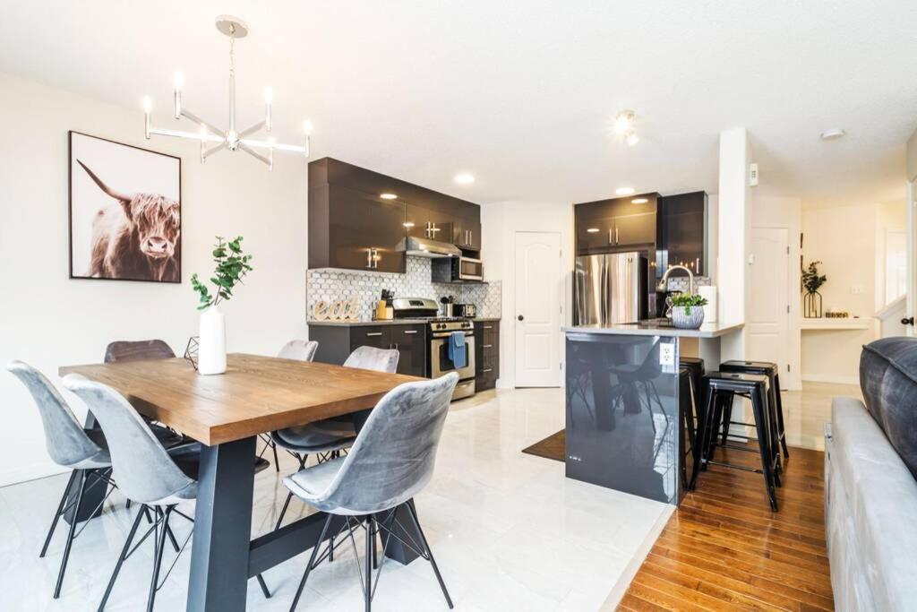 a kitchen and living room with a table and chairs at Chic 4 BDRM Home I King Bed I Double Garage Parking & Fast WiFi! in Edmonton