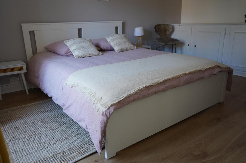 uma cama com lençóis e almofadas roxos e brancos em un dimanche chez Julie chambre Célestine em Parthenay