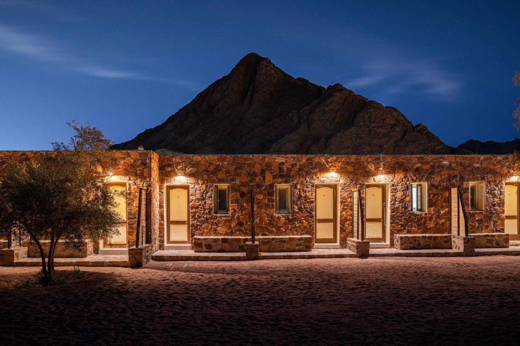 un antiguo edificio de piedra con una montaña en el fondo en Sheikh Mousa Bedouin Camp, en Saint Catherine