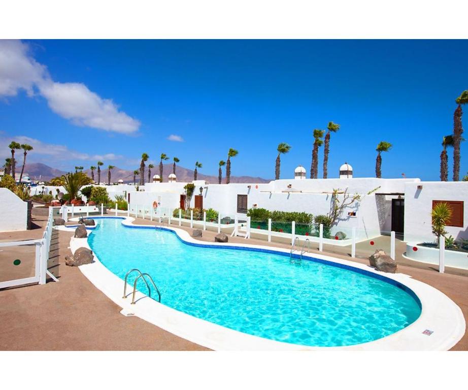 een groot zwembad in een resort met palmbomen bij Puerto Chico Y in Playa Blanca
