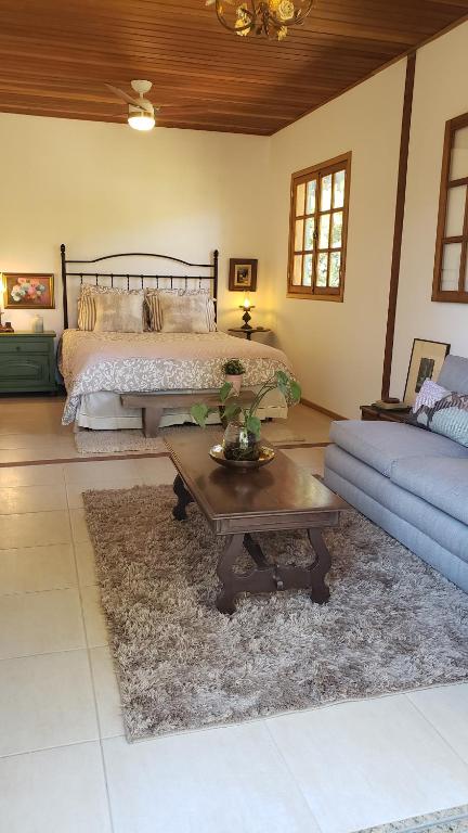 - une chambre avec un lit, une table et un canapé dans l'établissement Chácara das Lendas e Canções, à Passa Quatro