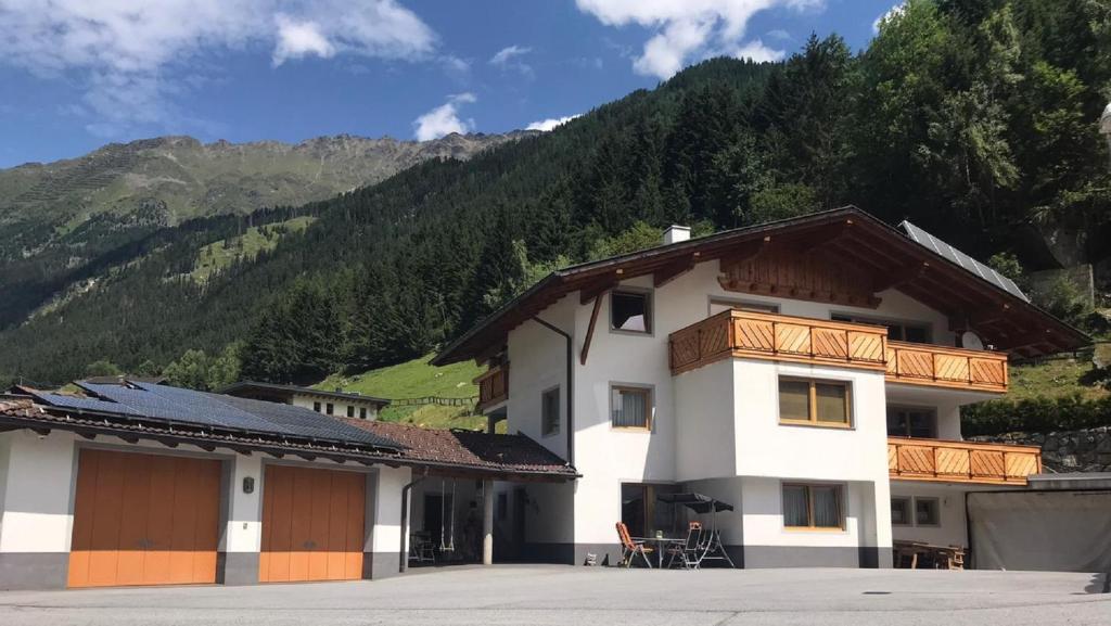 un gran edificio blanco con una montaña en el fondo en Ferienwohnung Sturm Pitztal, en Enzenstall