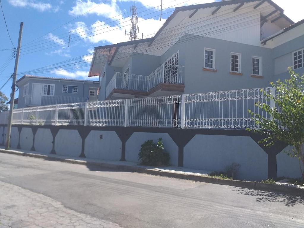 ein weißes Gebäude mit einem weißen Zaun neben einer Straße in der Unterkunft Vilarejo da Esperanza in Campos do Jordão