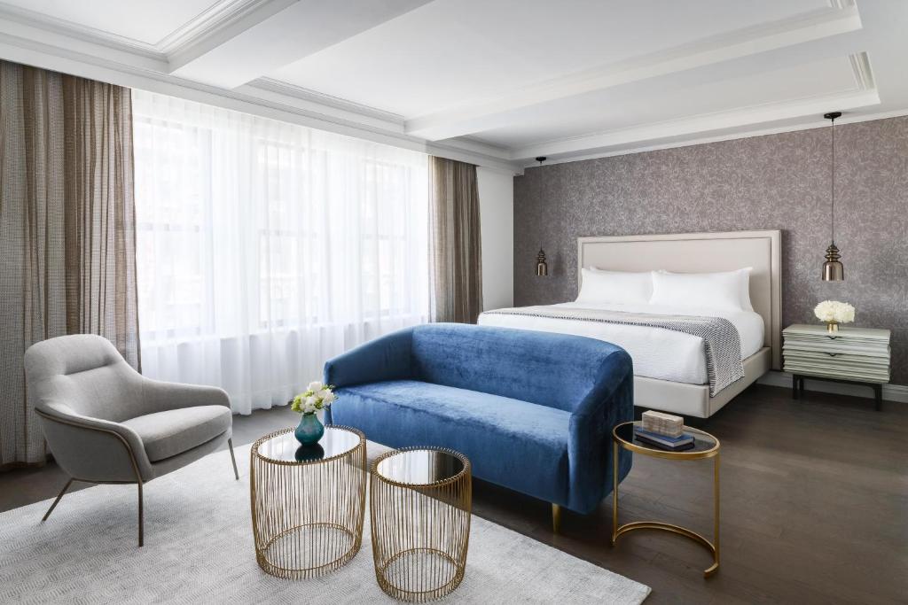 una camera d'albergo con un letto e un divano blu di The Wallace Hotel a New York