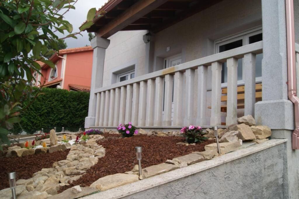 a garden in front of a house with rocks and flowers at As Campanillas in Cabana de Bergantiños