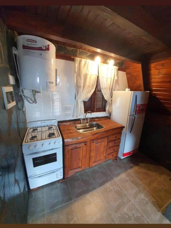 a kitchen with a stove and a sink and a refrigerator at Cabañas kymey in San Clemente del Tuyú