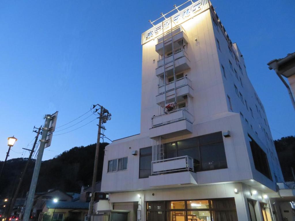 a tall white building with a balcony on it at 釜石駅から徒歩5分ホテルマルエHotelMarue in Kamaishi