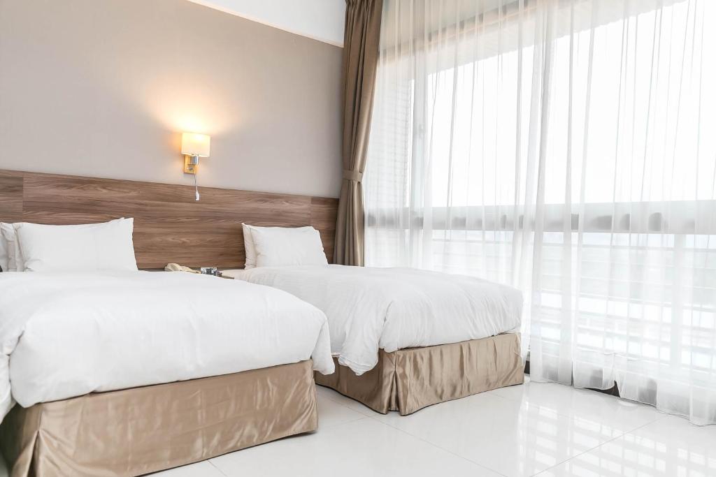 a hotel room with two beds and a window at Hotel Leisure Beitou in Taipei