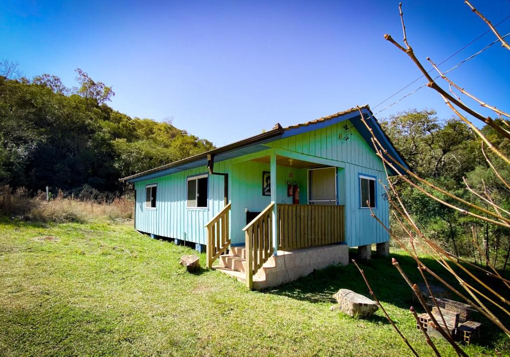 a blue and green house in a field at Casa colonial azul Santuário Bellatrix in Ribeirão Amarelo