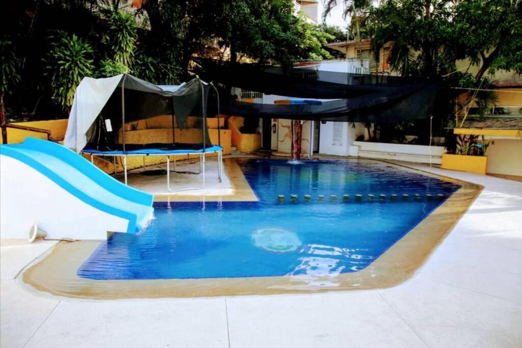 a large swimming pool with a slide and a slide at Condominio familiar y exclusivo Tres Mares in Acapulco
