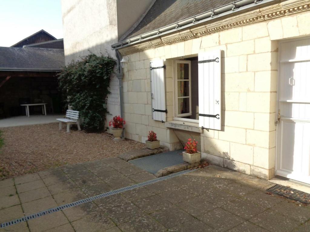 een wit bakstenen huis met een deur en een bank bij Gîte Restigné, 4 pièces, 6 personnes - FR-1-381-236 in Restigné
