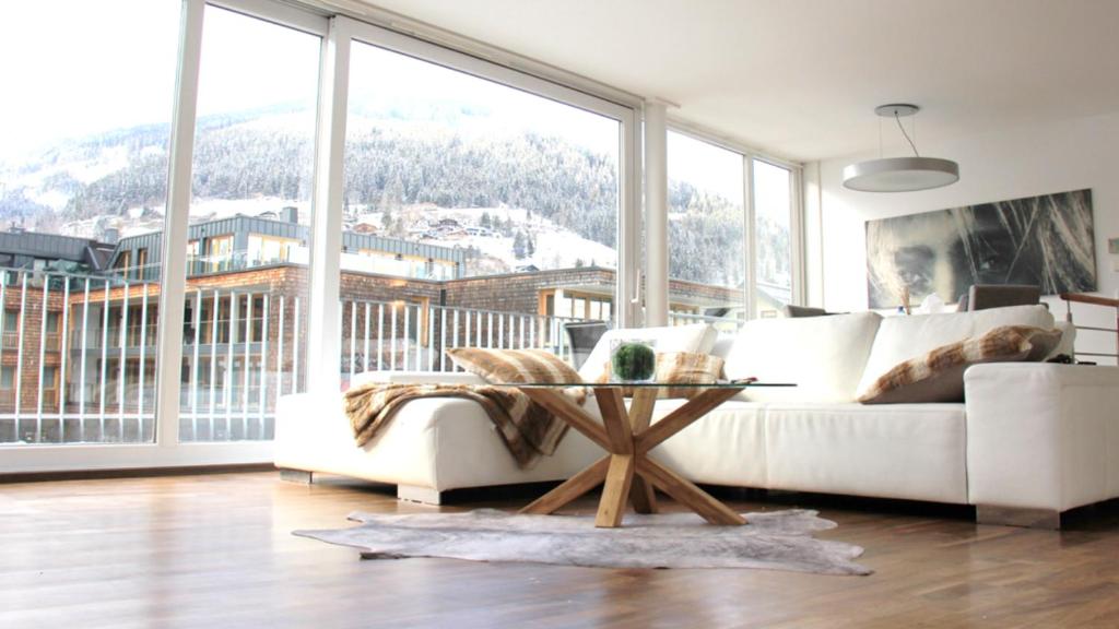 ein Wohnzimmer mit einer weißen Couch und einem großen Fenster in der Unterkunft Panorama Penthouse sermoreal in Zell am See