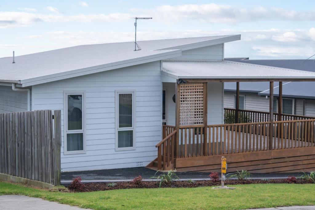 a white house with a wooden deck at Port View Escape in Bridport